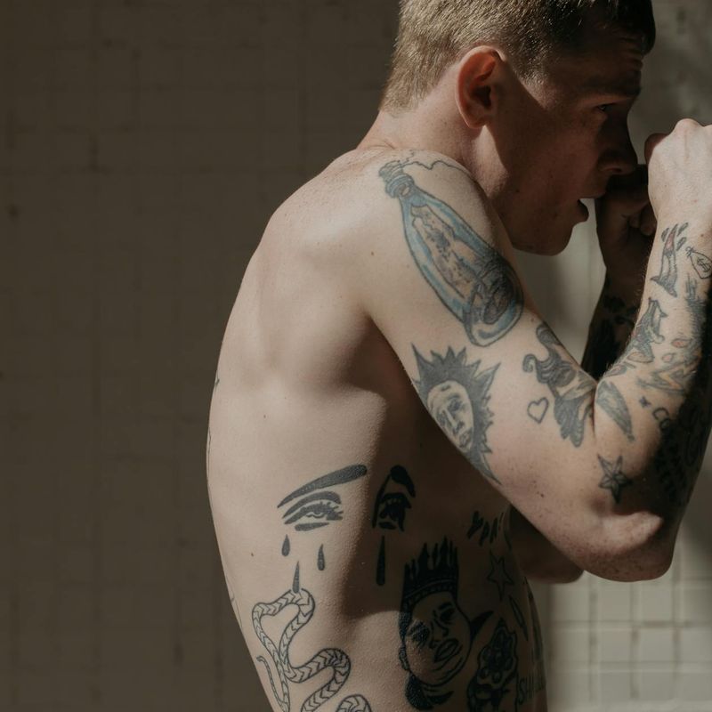 Man in a focused stance, mid-exercise, with strong neon mint light from one side.