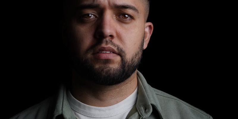 Wide shot of a person holding a difficult bodyweight pose in a spacious, dark room.